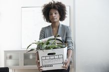 Businesswoman packing up box in office after receiving a termination letter.