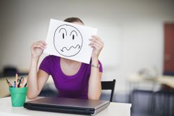 negative employee holds face frown picture over her face