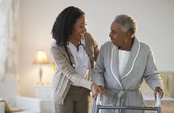 Nurse aiding woman with walker