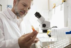 Male medical lab technologist examining sample in test tube