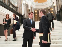 Smiling lawyers shaking hands in front of stairs at a courthouse