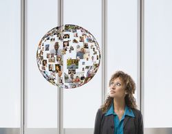 Businesswoman With Floating Globe of Faces