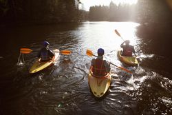 Kayakers rowing together on still lake