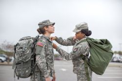 Female Soldier Helping Another Soldier with Shirt