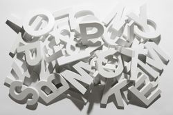 A pile of various white block letters from the alphabet