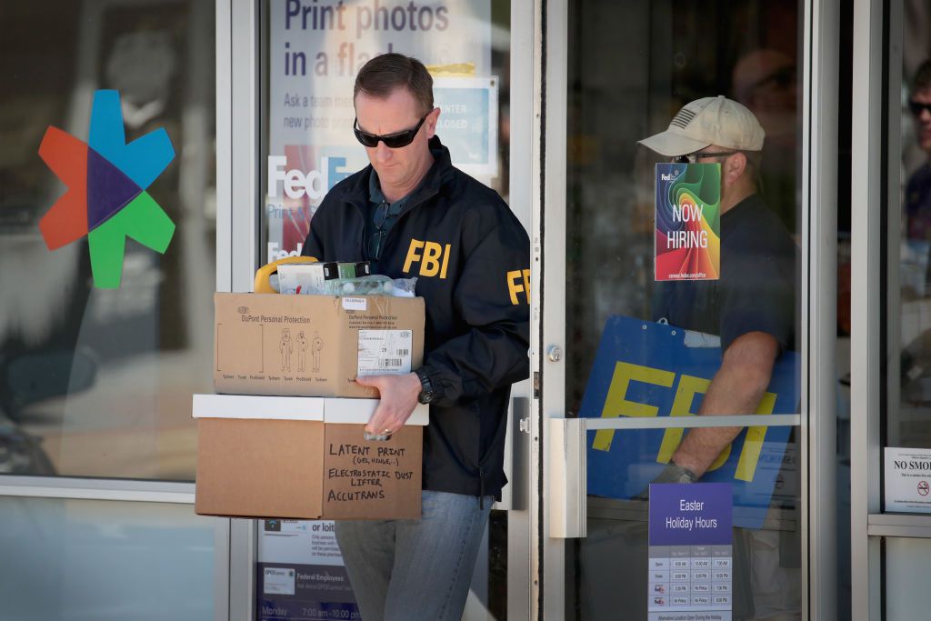 Agent for the FBI removes boxes of equipment from a building