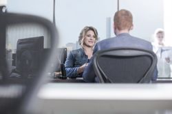 Woman and man talking at desk in office during employee evaluation