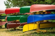 Colorful kayaks and canoes by the lake on a sunny day.