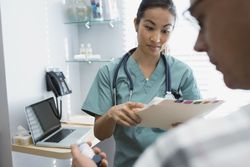 Nurse reviewing medical chart with patient holding inhaler