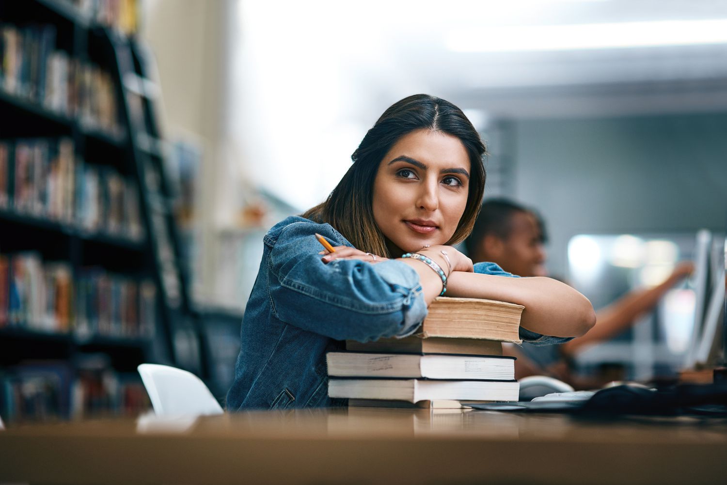 Young woman college student looking thoughtful in library.