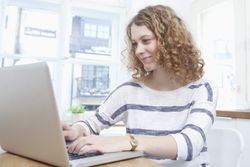 Woman using laptop to write a new job announcement letter to her clients.