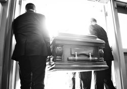 Two pallbearers carrying a casket