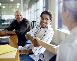 Businessman and businesswoman shaking hands at conference table