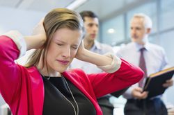 Frustrated worker covers their ears as bosses argue