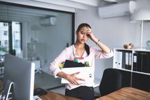 Shot of an unhappy businesswoman holding her box of belongings after getting fired from her job