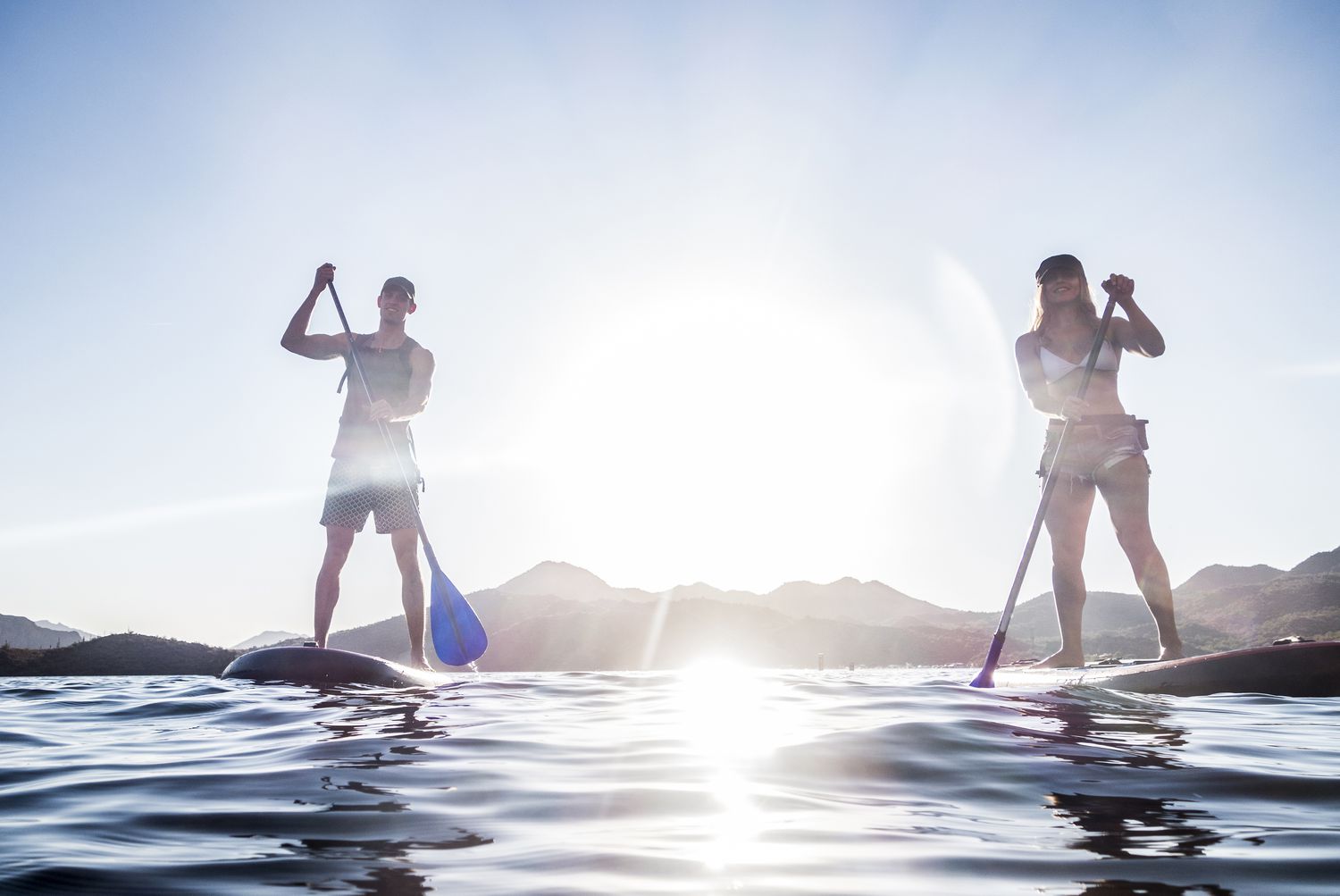 Couple standing on paddleboards in river