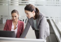 Two women work on learning the new Human Resources Management Information System (HRIS)