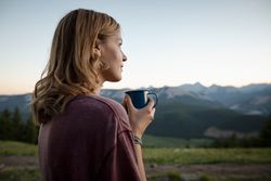 Thoughtful, serene woman drinking coffee and looking at mountain view, Alberta, Canada