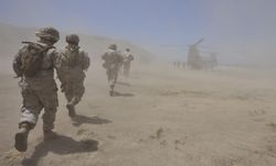 Marines move through a dust cloud toward a CH-46 Sea Knight.