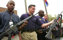 ATF special agents holding up rifles they confiscated during a raid.