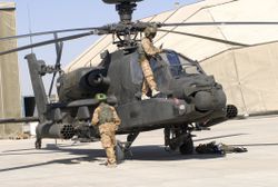 Two soldiers repairing an Apache AH-64 helicopter.