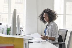 Side view of businesswoman holding letter and sitting at desk