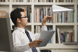 young businessman throwing paper airplane