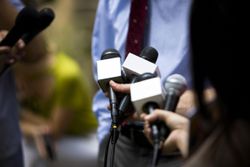 A picture of reporters holding microphones and interviewing someone