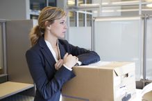 Woman with moving boxes in office, thinking