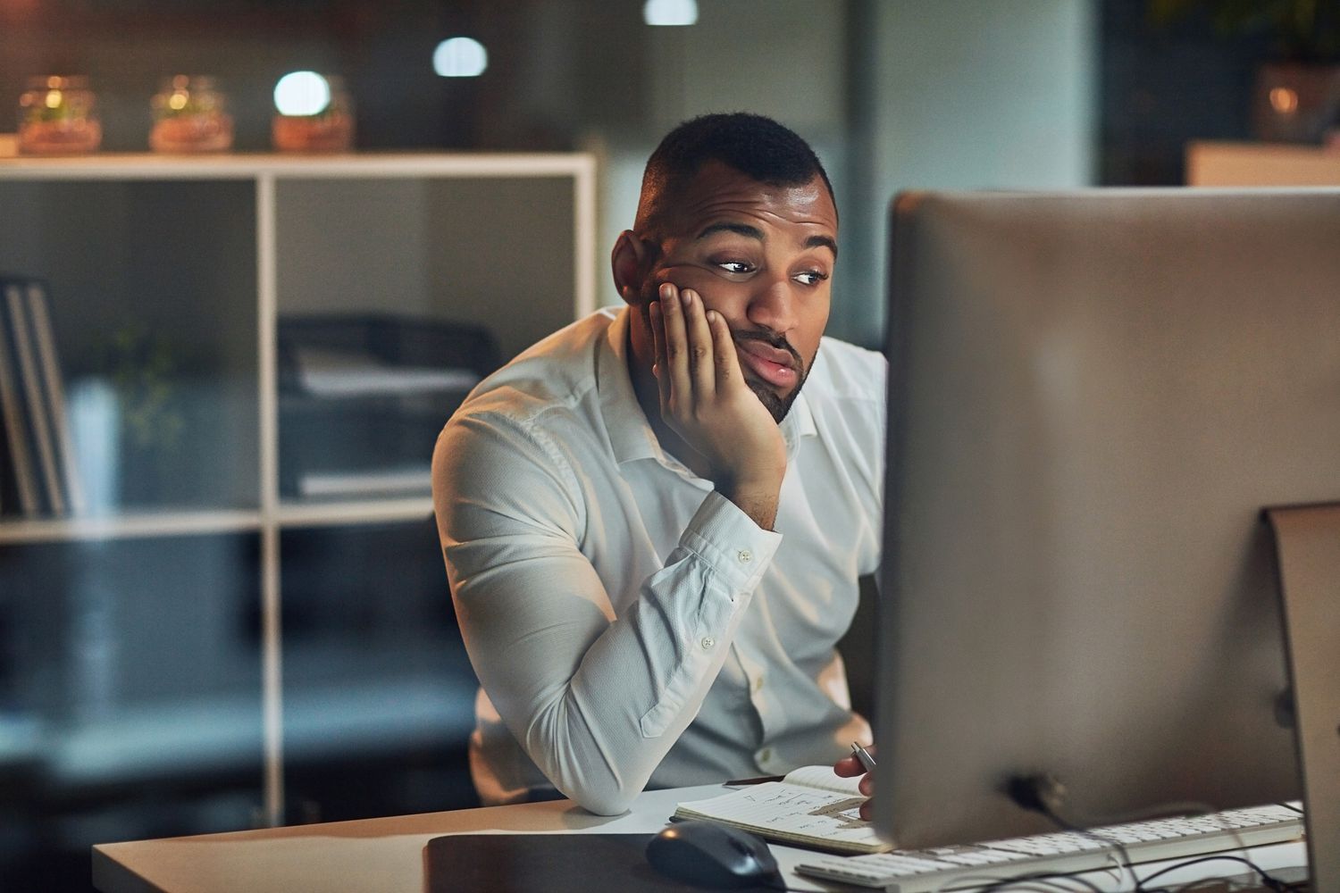 Man looking at computer screen resting his chin in his hand.