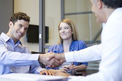 Businessman shaking hands with young man while young woman watches