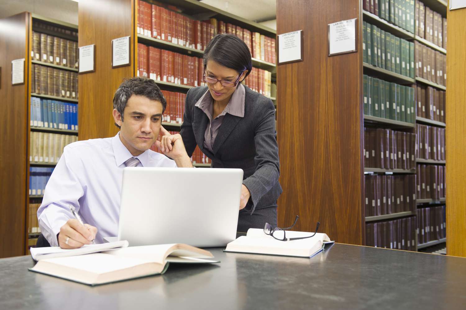 Two lawyers in a library in front of a laptop