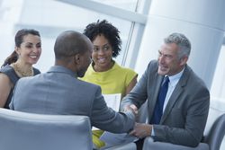 business people sitting in a circle chatting, two men shaking hands