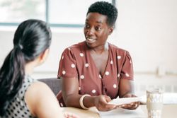 Manager speaking with an employee at a table.