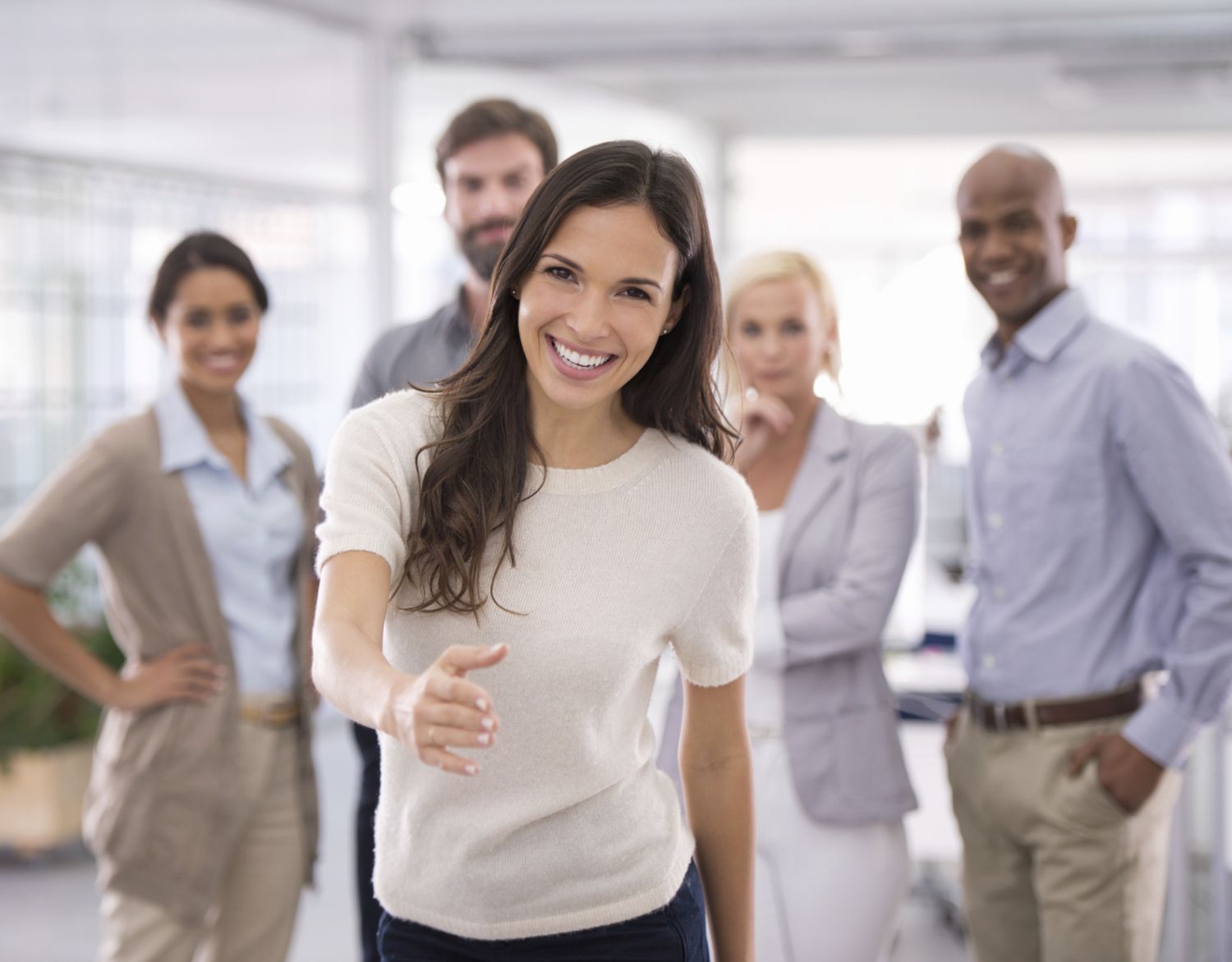 Joyful woman with her team welcome you to her workplace with joy