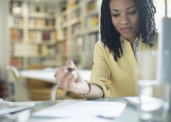 Business woman writing on paper in her office.