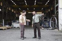 Factory manager and worker arguing in front of warehouse