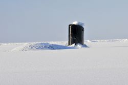 Navy submarine surfacing through an ice sheet in the Arctic during operations.