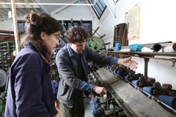 Weaver showing apprentice how to use cone winder