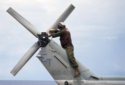 A Marine conducts maintenance on the tail of an UH-1N Huey helicopter.