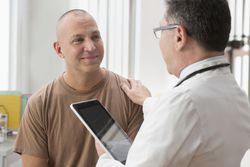 Caucasian soldier and doctor talking in office