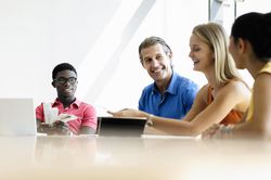 Coworkers discussing plans an laptops in office