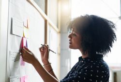 Woman setting goals and making plans with adhesives on whiteboard