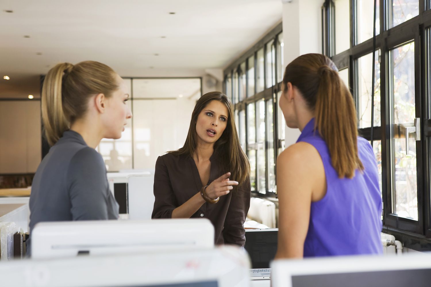 Three women in office having an argument that is causing negativity in their workplace.