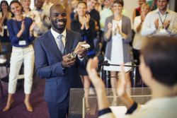 Black male employee is formally recognized for his contribution with a recognition trophy.