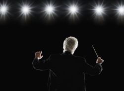 Man in tuxedo conducting under lights