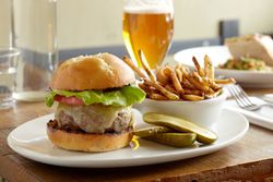 Burger, fries, and pickles with a beer on a restaurant table