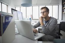 Focused software tester working at laptop in office