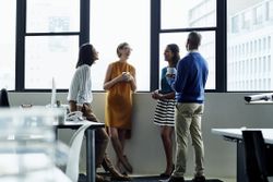 Cheerful co-workers standing by office window before the start of a business day.