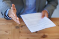 man holding resume reaching out hand for handshake